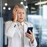 Elderly businesswoman looking worried at her smartphone screen