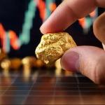 Une main tenant une pépite d'or avec un graphique financier en arrière-plan