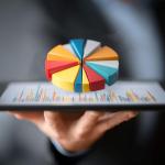 Hand met een tablet waarop een kleurrijke taartdiagram wordt weergegeven