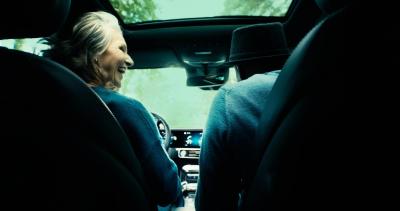  An elderly couple shares smiles and glances at each other as they enjoy a trip together, cruising in their car and cherishing the moments of companionship.
