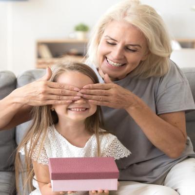 Grandmother covering her granddaughter's eyes to hide a gift.