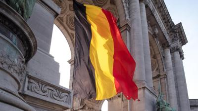 Mother and child looking at a Belgian flag with monument in the background