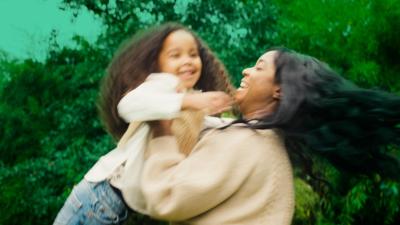  A young mother delights in spinning her daughter around in the garden, creating moments of joy and laughter in their playful interaction.