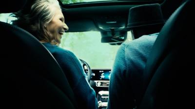  An elderly couple shares smiles and glances at each other as they enjoy a trip together, cruising in their car and cherishing the moments of companionship.