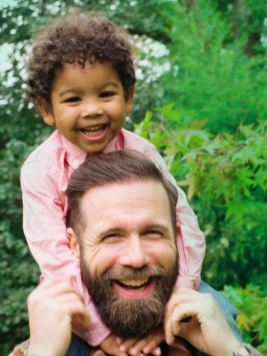 A child sits atop his father's shoulders, enjoying a playful and uplifting moment as they share a special connection.