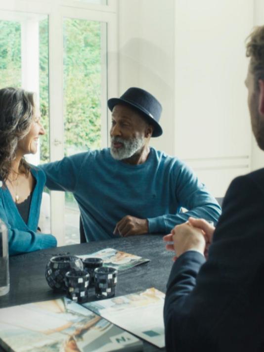 An elderly couple sits at a table, exchanging glances with one another while engaged in a meeting with their Nagelmackers advisor. Together, they focus on discussions about their financial matters, creating a collaborative and thoughtful atmosphere.