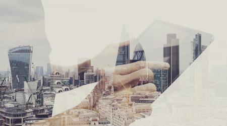 Double exposure image of a skyline and a person holding a tablet