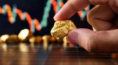 Une main tenant une pépite d'or avec un graphique financier en arrière-plan