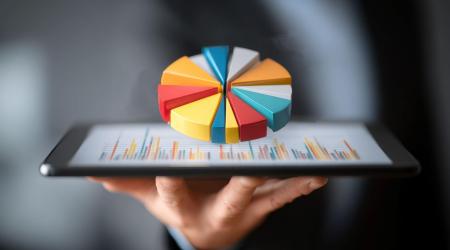 Hand met een tablet waarop een kleurrijke taartdiagram wordt weergegeven